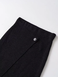Detailed close-up of charcoal knit midi skirt showing waist button and wrap design