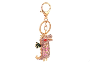 Détail d'un porte-clés dragon doré orné de cristaux roses brillants et de finitions émaillées