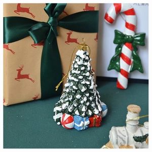Detail of Christmas tree ornament with white snow accents and a colorful gift box base