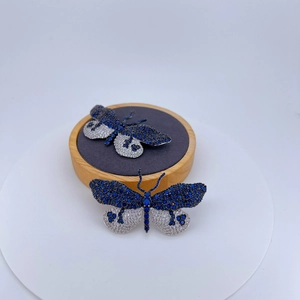 Broches papillon en zircon bleu et blanc étincelant sur un support en bois
