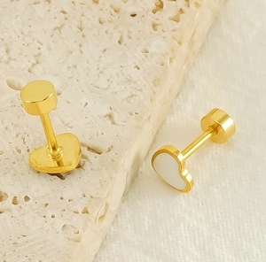 Détail de boucles d'oreilles cœur dorées avec émail blanc et fermoir plat type labret