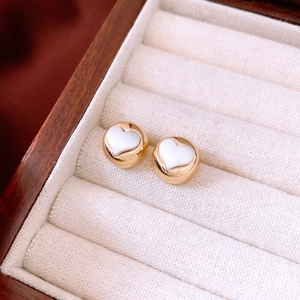 Macro shot of gold-tone heart stud earrings in a luxury velvet jewelry box