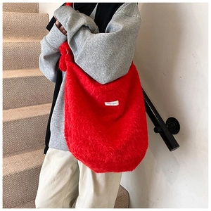 Macro detail of the fuzzy red faux fur texture and branded white label on the tote bag