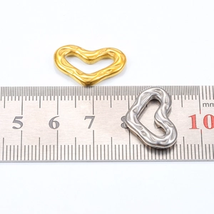 Macro view of 20mm heart pendants in gold and silver steel with hammered texture details