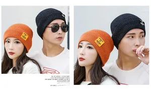 Close-up of ribbed knit beanies with ambition text labels in orange and dark grey colors