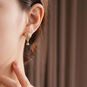 Boucles d'oreilles montgolfière dorées serties de zircons portées sur l'oreille