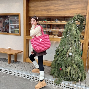 Détail d'un sac cabas en peluche rayé rouge et rose dans un décor festif de Noël chaleureux