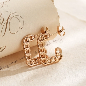 Golden geometric chain-link earrings with high-polish finish on vintage paper backdrop