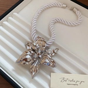 Detailed shot of silver flower pendant necklace with white woven cord in a jewelry gift box