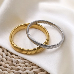 Details von gold- und silbernen Schlangenknochen-Armbändern auf Seide