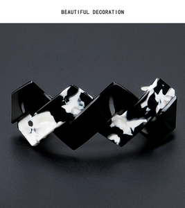 Detail view of large acetate hair clip with black and white geometric pattern and glossy finish