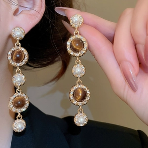 Detail of vintage gold earrings with tiger eye stone, pearls and crystal tassels