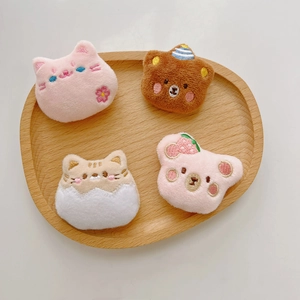 Detail of cute plush bear and cat brooches with exquisite embroidery on a wooden tray