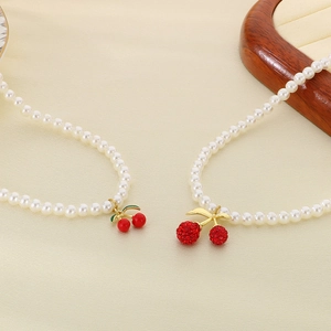 Cherry pearl necklaces with red resin and rhinestone pendants on yellow leather