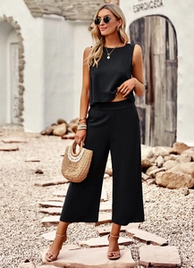 Detail of elegant black sleeveless top and cropped wide-leg pants set on female model