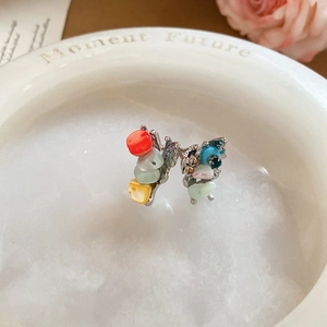 Detail of colorful stone earrings in silver base on a stone tray with pink roses