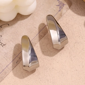 Detailed view of minimalist polished silver curved earrings on aesthetic card background