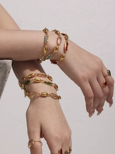 Detailansicht von luxuriösem buntem Edelsteinarmband und Goldring am Modellarm