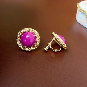 Detail view of vintage gold screw-on clip earrings with purple cabochon stones
