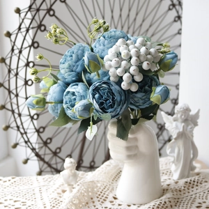 Blue artificial peony bouquet in a white hand-shaped ceramic vase for home decor