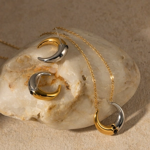 Detail of gold and silver two-tone crescent jewelry set with black zircon on white rock