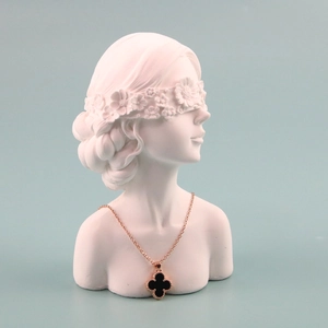Artistic white female bust display showing a black clover necklace with gold chain detail