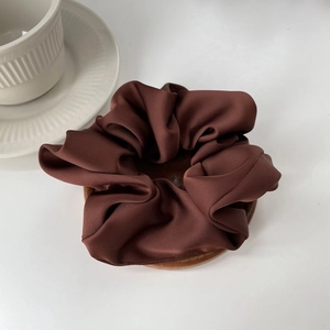 Detail shot of a dark coffee satin silk scrunchie with elegant French fold texture