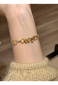Detailed view of yellow citrine and silver beaded bracelet on a soft knitted sweater