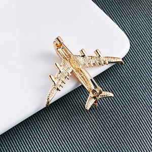 Detailed view of golden alloy airplane brooch featuring a textured metallic finish and pin