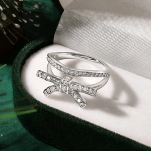 Macro view of a silver double-layered bow ring with sparkling zircons in a velvet gift box