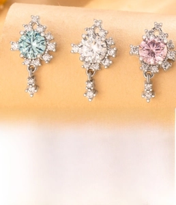 Detail view of flower-shaped titanium steel ear studs with zircon stones in three colors