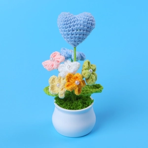 Detailed view of a handmade crochet heart plant with colorful flowers in a white ceramic pot