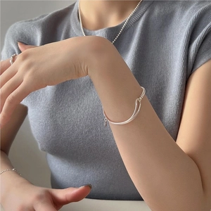 Close-up of minimalist S925 sterling silver beaded bracelet and geometric ring on model