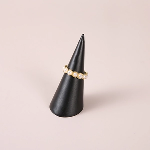Elegant gold ring with white pearls displayed on a black resin conical stand