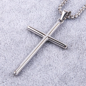 Macro detail of polished silver stainless steel cylindrical cross pendant and box chain