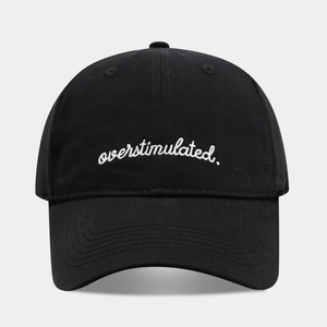 Detailed close-up of white 'overstimulated' embroidery on a black baseball cap