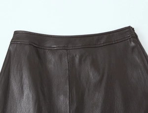 Dettaglio della gonna midi in ecopelle marrone scuro con cuciture in vita e zip invisibile