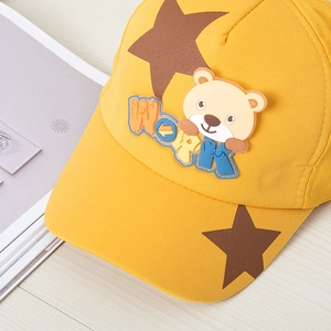 Détail d'une casquette jaune pour enfant avec étoile brune et patch ours 3D en gomme