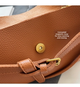 Detail of brown litchi pattern leather bag with golden magnetic buckle and strap buckle