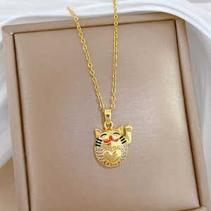 Elegant gold titanium lucky cat necklace with sparkling diamonds on soft silk fabric