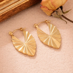 Détails des boucles d'oreilles dorées en U torsadées sur feutre beige avec décor