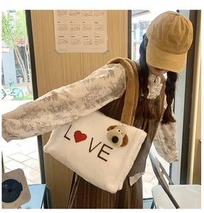 White faux fur tote bag with brown straps and red heart LOVE print being worn by a model