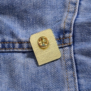 Golden alloy heart book brooch with butterfly clasp on blue denim jacket