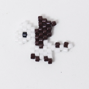 Macro shot of handmade pixelated dinosaur bead charm for jewelry making accessories