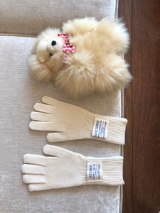 Detalle de guantes táctiles de lana tejida beige con etiquetas sobre una tela suave