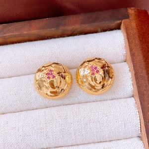 Macro detail of vintage 18k gold plated round earrings with red gemstone flower center