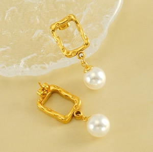 Close-up of gold square hammered metal pearl earrings with elegant texture