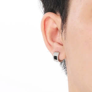 Close-up of a silver stainless steel hoop earring with black square inlay on human ear