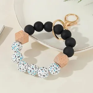Detail of silicone and wood beaded keychain wristlet with gold lobster clasp on white tray