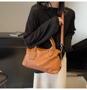 Close-up of brown litchi pattern leather bag with adjustable strap and metal hardware
